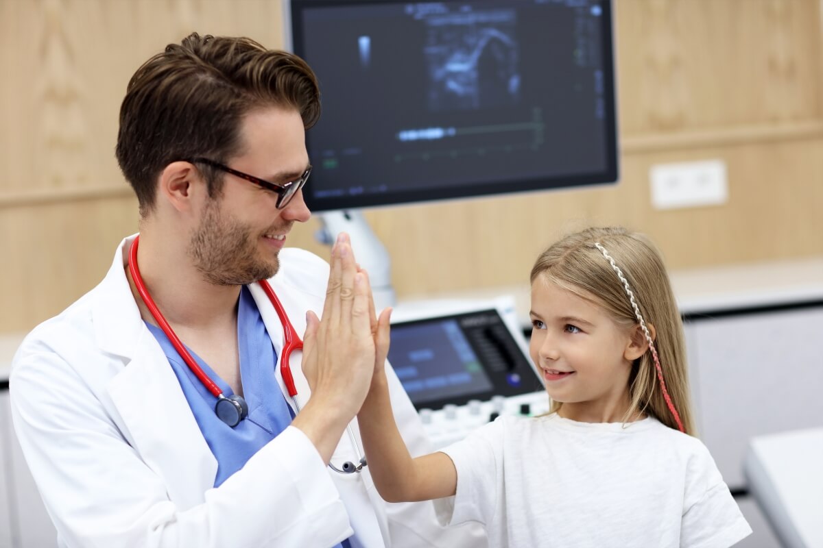 Lekarz w białym kitlu przybija piątkę z dzieckiem, urolog dziecięcy.