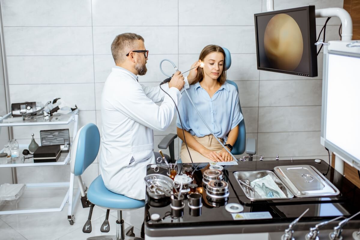 Otolaryngolog sprawdza ucho pacjentki w gabinecie.