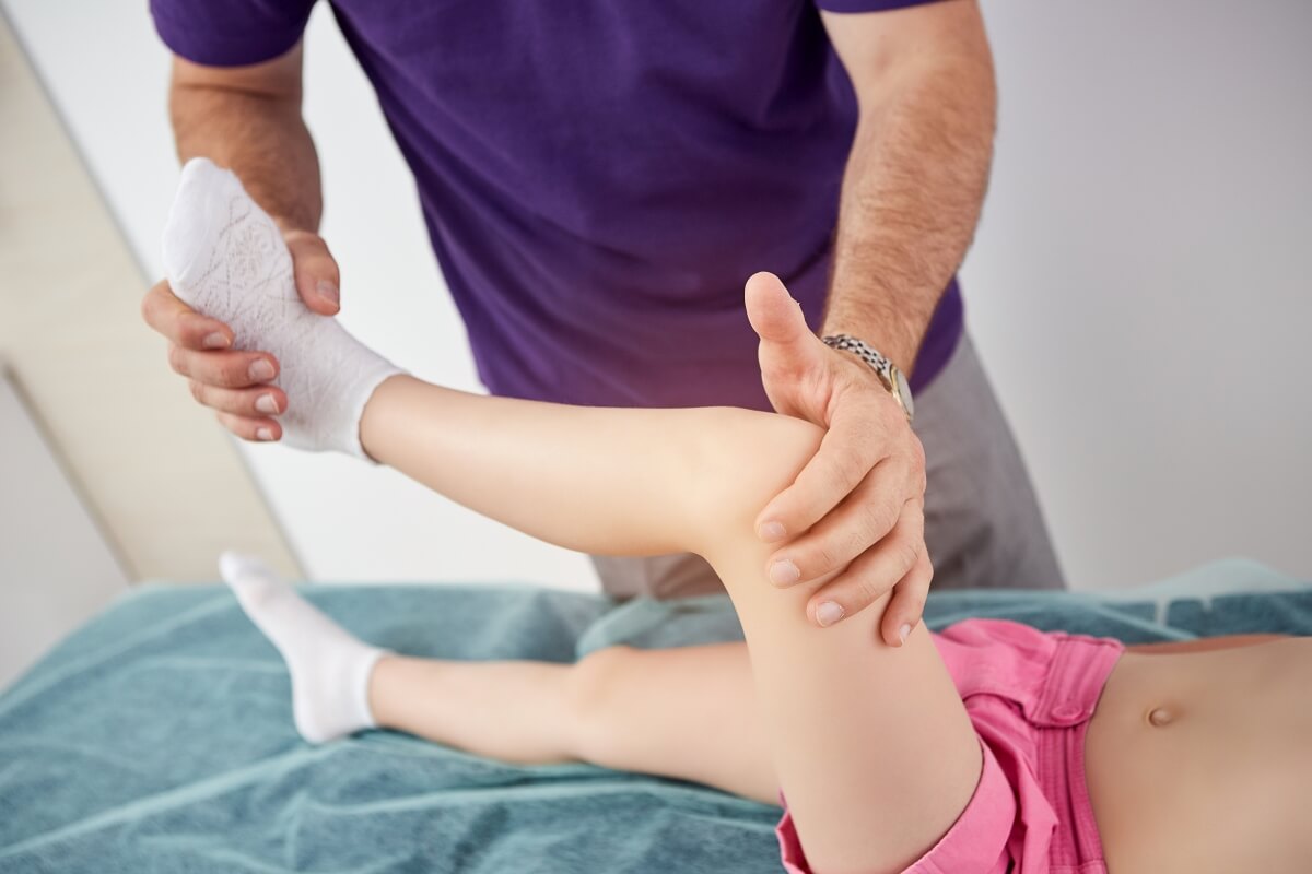 Dziecko poddawane jest zabiegowi fizjoterapii, co jest częstą praktyką w medycynie sportowej dziecięcej.