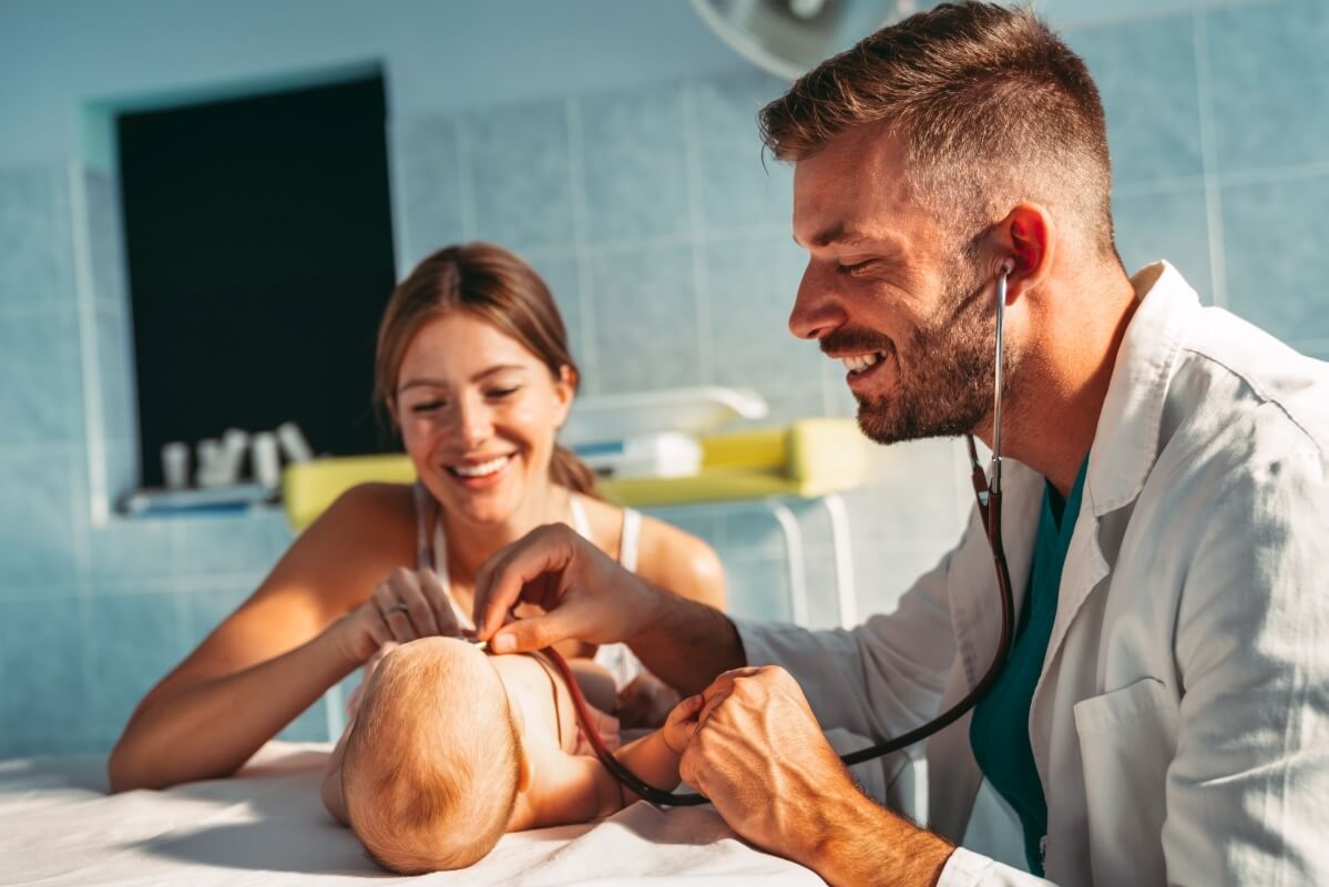 Lekarz w gabinecie pediatrycznym bada dziecko, podczas gdy matka uśmiecha się.