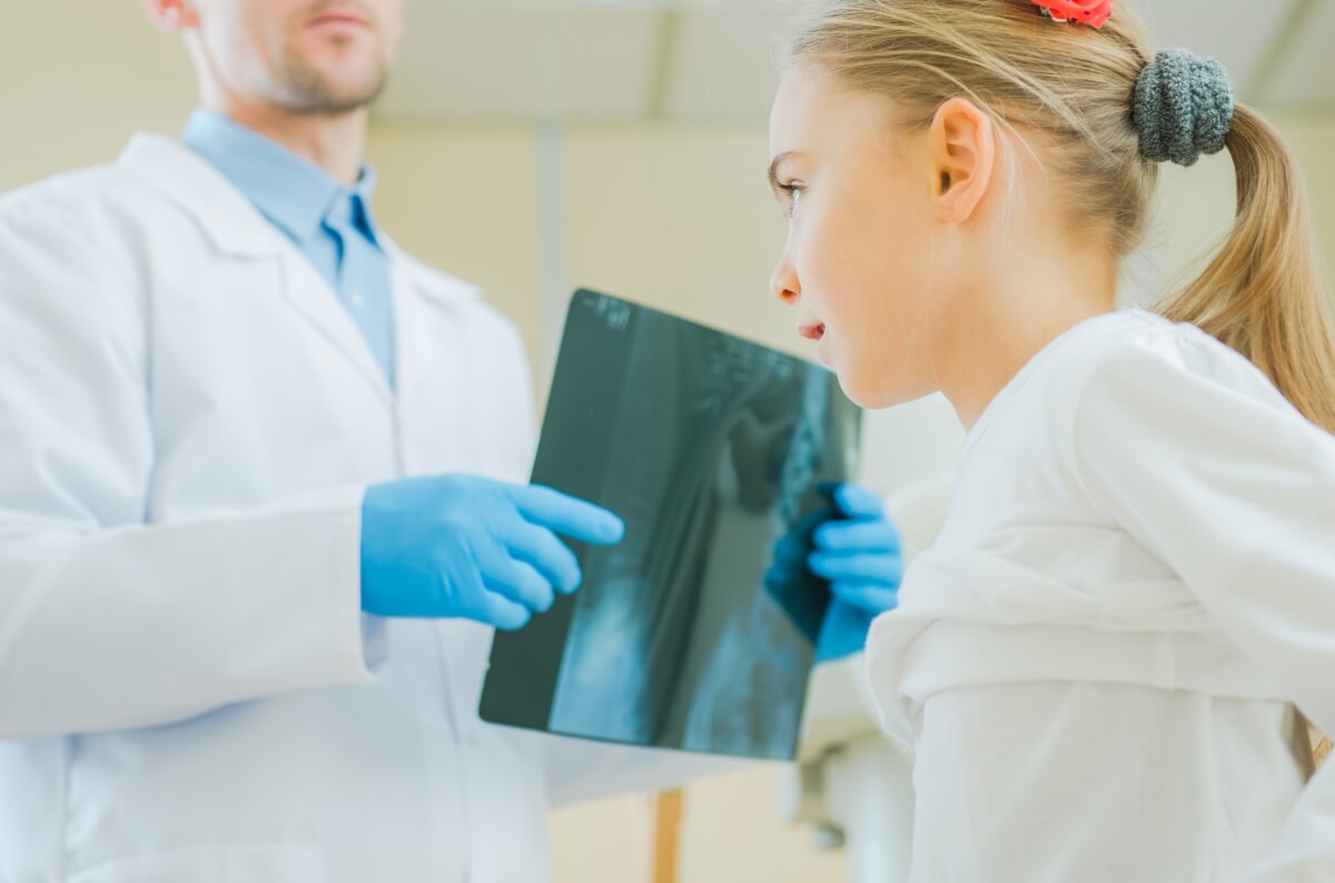 Ortopeda pokazuje zdjęcie rentgenowskie młodej pacjentce.